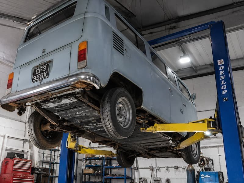 Van on a two post lift in a workshop bay at CF3 MOT and Service Centre in Rumney, Cardiff, being inspected for structural corrosion.