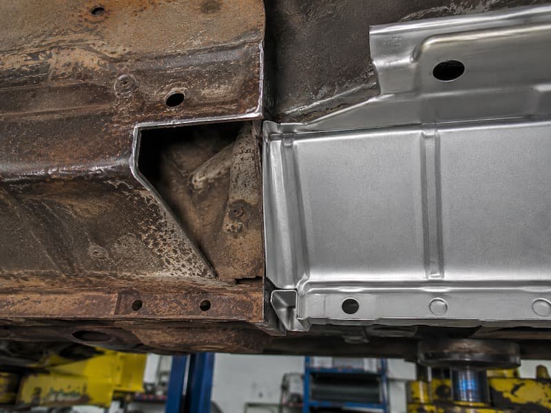 Corrosion repair in progress on a van sill panel, showing the cut back to sound metal with the rotten section removed and the replacement section ready to weld in.