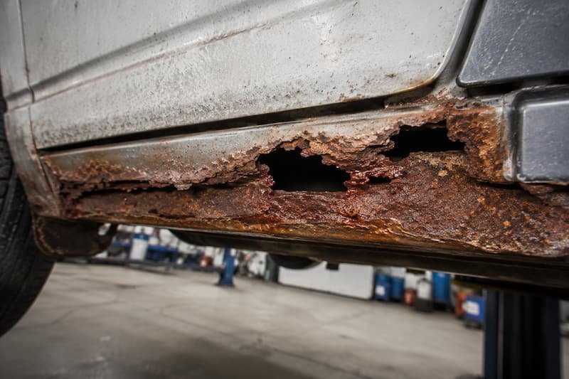 Deep red corrosion along the lower edge of a VW T25 sill with a hole perforated right through the metal.