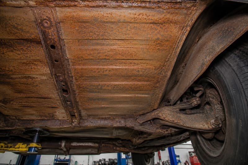 Wide area surface corrosion across the floor pan and inner wheel arch of a VW T25, with no perforation visible.