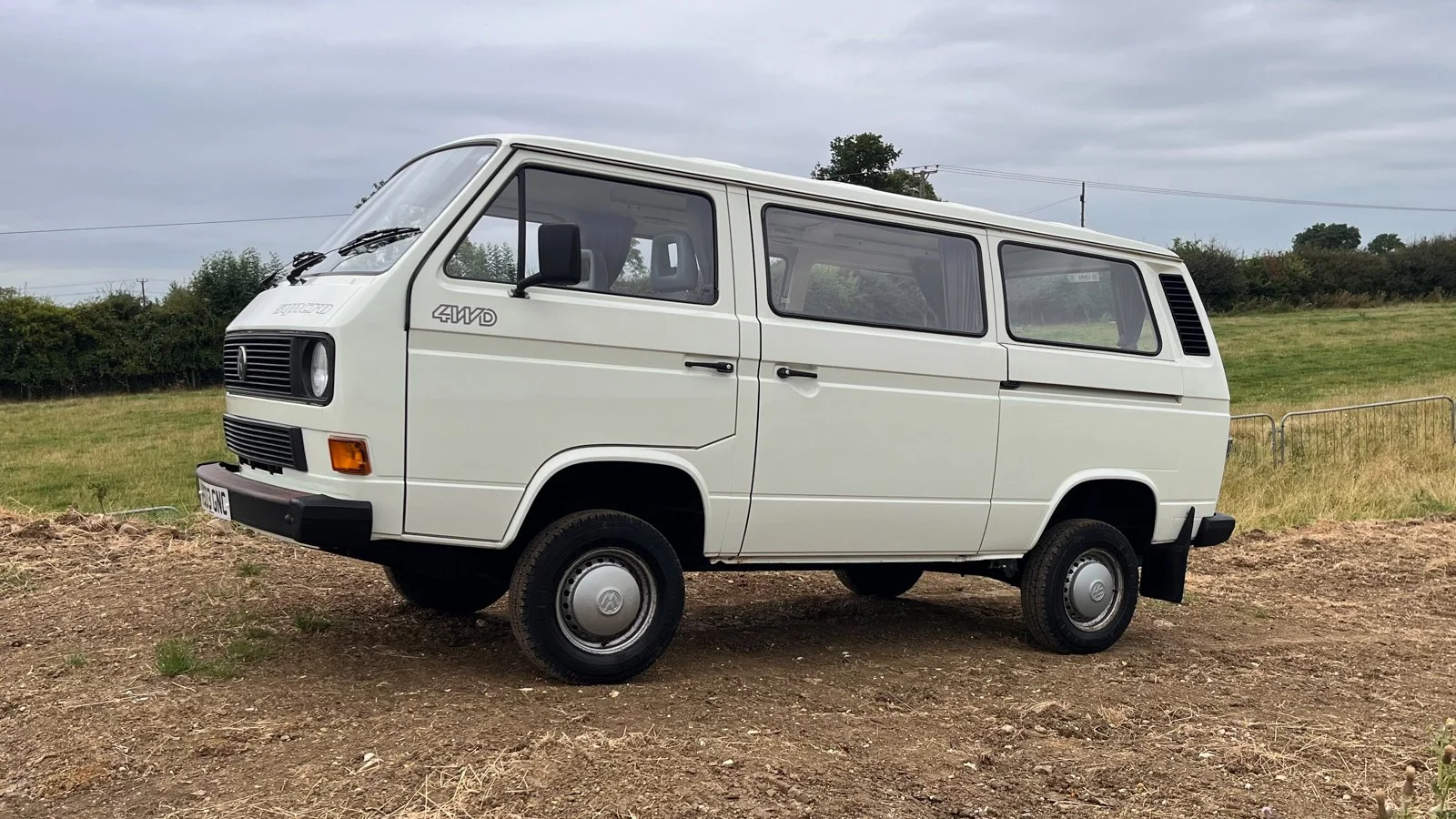 White Volkswagen T25 van in a workshop bay at CF3 MOT and Service Centre in Rumney, Cardiff, with a trade plate fitted and the cab door open.