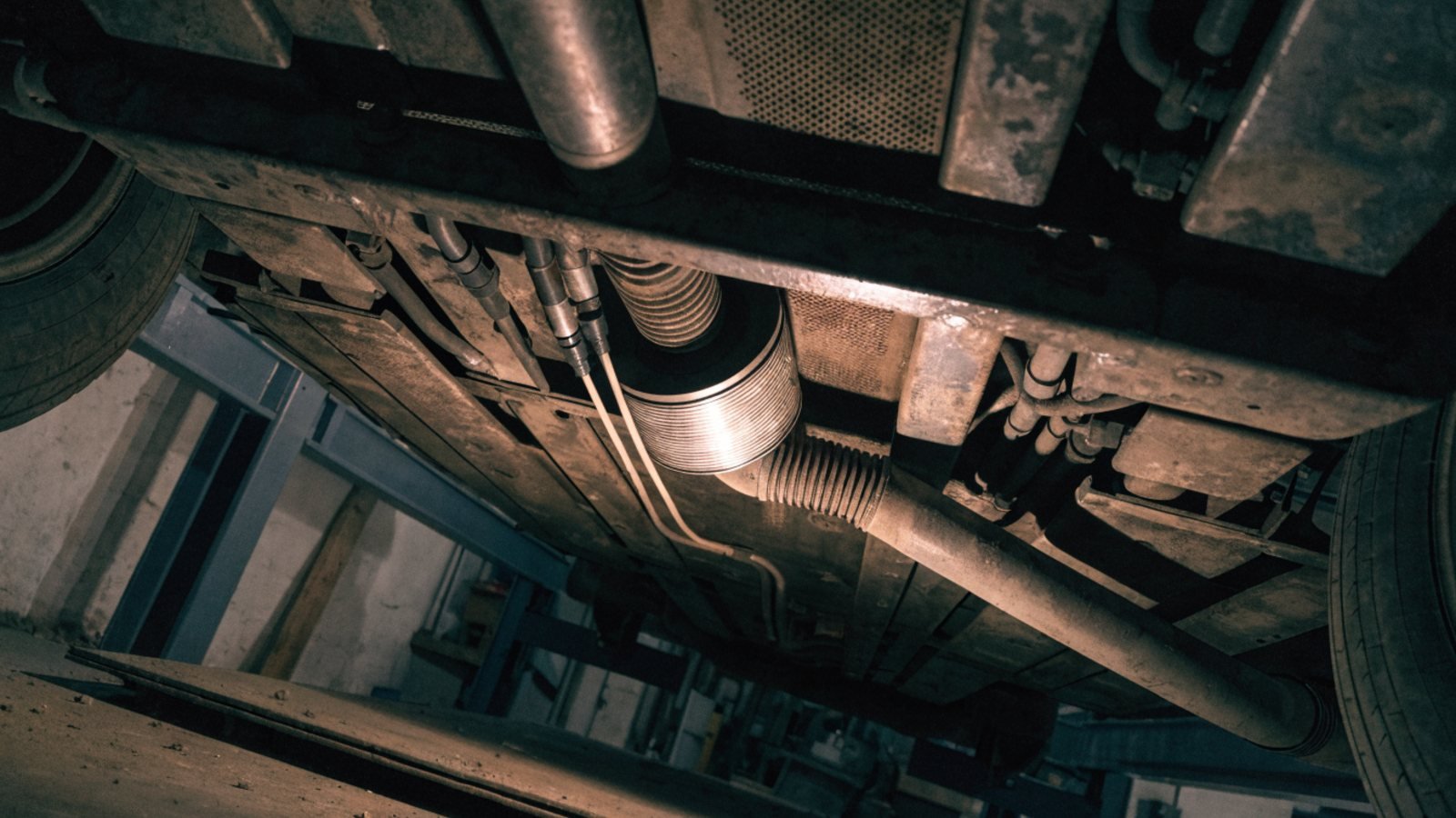 Underside of a diesel car on a lift showing the exhaust system with the particulate filter canister and sensor pipes
