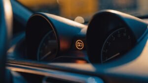Car instrument cluster at night with an amber engine warning symbol lit between the dials