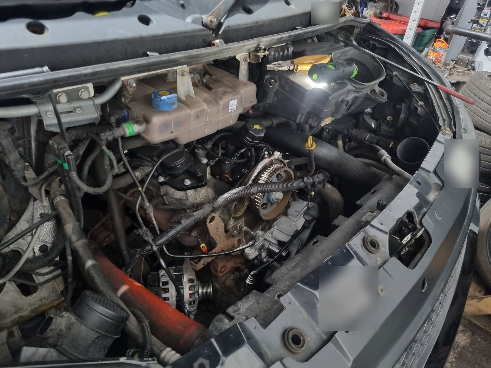 Front end of an Iveco van stripped down in the CF3 MOT and Service Centre workshop in Rumney, with the timing belt removed and the camshaft pulley exposed ready for a new belt kit and water pump.