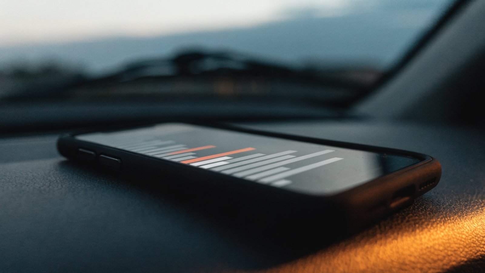 Smartphone resting on a car dashboard at dusk showing a calendar with evening time slots highlighted