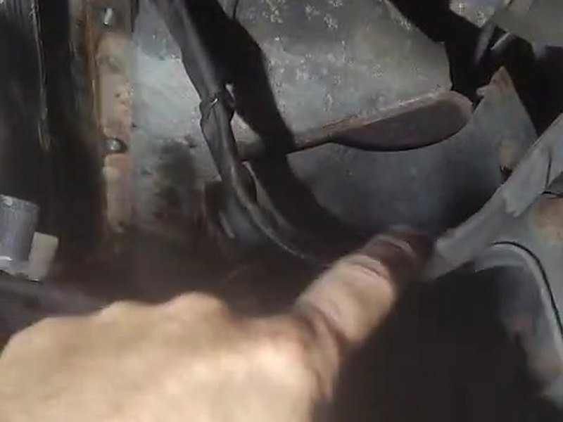 Technician hand under an Iveco van pointing to the narrow gap between the corroded subframe and the engine sump.
